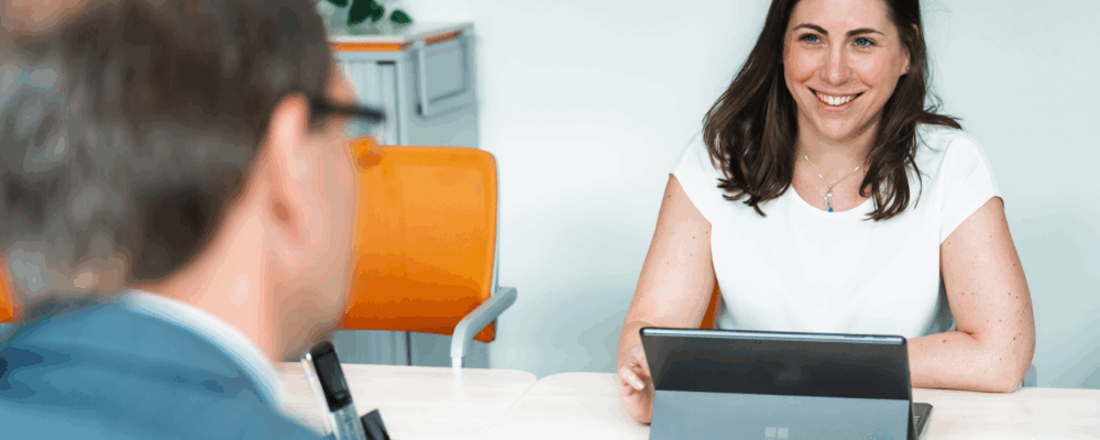 Zwei Personen im Gespraech am Schreibtisch mit Laptop