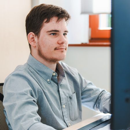 Ein Mitarbeiter der Benke Steuerberatung sitzt am Computer und arbeitet konzentriert an seinem Arbeitsplatz.