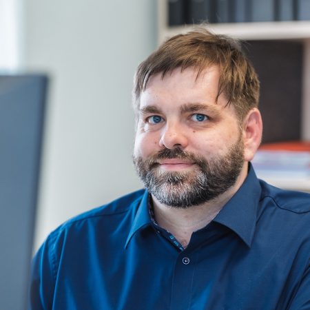Ein Mitarbeiter der Benke Steuerberatung blickt freundlich in die Kamera und sitzt an seinem Arbeitsplatz im Büro.